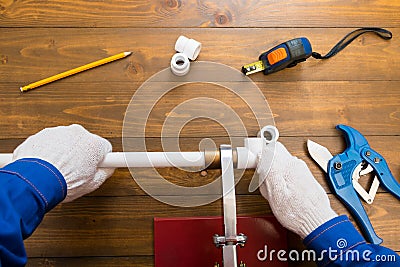 Gloved hands glue two pieces of plastic water pipe Stock Photo