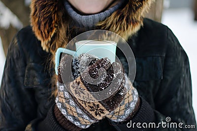 Gloved hands holding a cup of tea outdoors Stock Photo