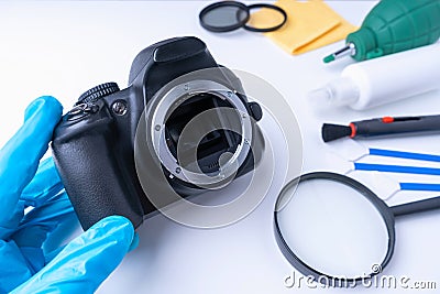 A gloved photographer holds his DSLR camera without a lens before cleaning the sensor Stock Photo