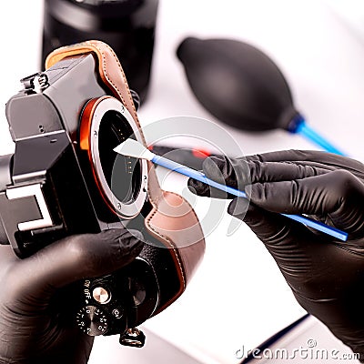 A gloved photographer takes care of photographic equipment with special tools. Stock Photo