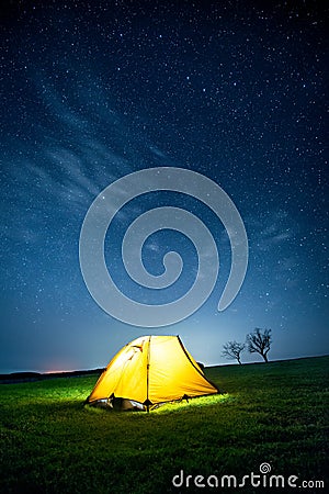 Glowing camping tent in the night mountains under a starry sky Stock Photo