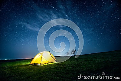 Glowing camping tent in the night mountains under a starry sky Stock Photo