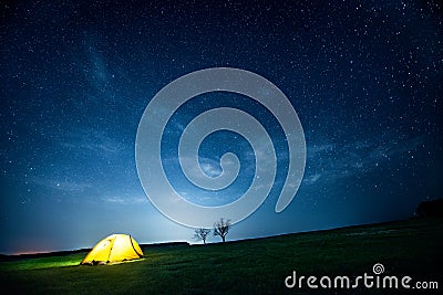 Glowing camping tent in the night mountains under a starry sky Stock Photo