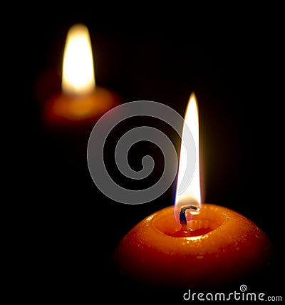 Glowing candle and its reflection in the dark Stock Photo