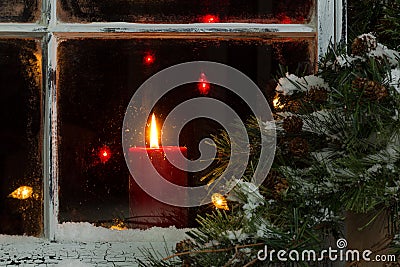 Glowing Christmas candle in frosted home window Stock Photo