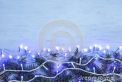 Glowing Christmas lights and fir branches on wooden background Stock Photo