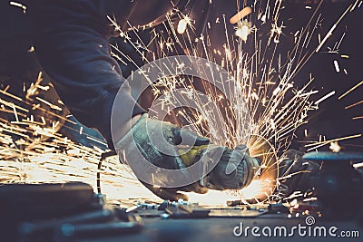 Glowing flow of sparks made by sawing a piece of steel with an angle grinder on a work surface Editorial Stock Photo