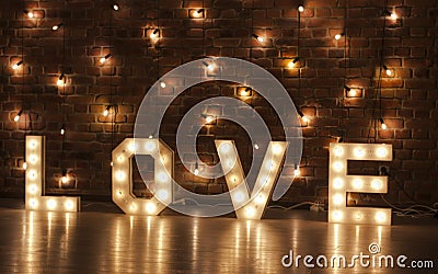 Glowing letters of love against a backdrop of lights and brick walls Stock Photo