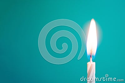 Glowing thin white candle on blue background Stock Photo