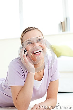 Glowing woman talking on phone lying on the floor Stock Photo