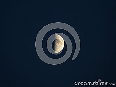 Glowing yellow half moon in a dark blue night sky Stock Photo