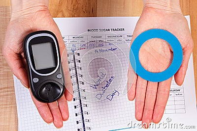 Glucometer and blue circle in hand, symbol of diabetic, world diabetes day Stock Photo