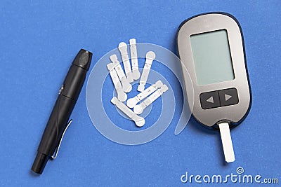 Glucometer with a needle on a blue background. Measurement of blood glucose Stock Photo