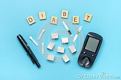 glucometer, sugar cubes on blue background High blood sugar and diabetes concept Top view Flat lay 14 November - World Diabetes Stock Photo