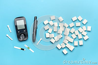 glucometer, sugar cubes on blue background High blood sugar and diabetes concept Top view Flat lay 14 November - World Diabetes Stock Photo