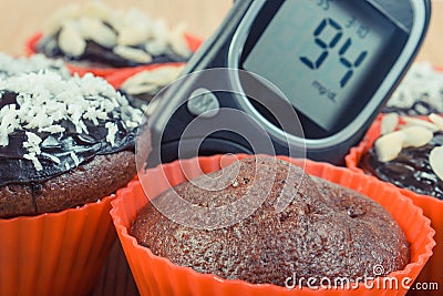 Glucose meter for checking sugar level and fresh chocolate muffins. Diabetes and dessert for different occasions Stock Photo