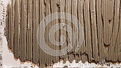 Glue for a tile with a gear pattern. Installation of tiles. The surface of the wall is covered with adhesive paste before laying Stock Photo