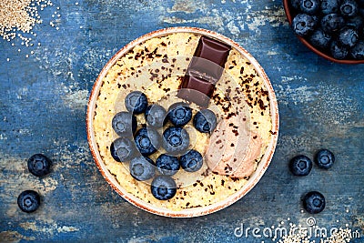 Gluten free amaranth and quinoa porridge breakfast bowl with blueberries and chocolate over rustic wooden background. Stock Photo