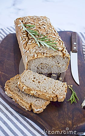 Glutenfree buckwheat bread with a golden brown crust, sprinkled with sunflower seeds, lies on a wooden table. Healthy homemade Stock Photo