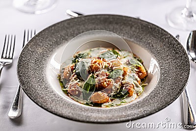 Gnocchi pomodoro with mascarpone, cream, basil and parmesan, in a stylish plate on a restaurant table Stock Photo