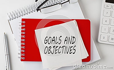 GOALS AND OBJECTIVES word on sticker on notepad with pen and calculator Stock Photo