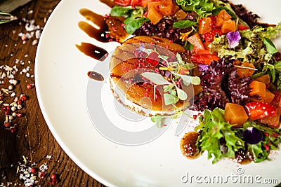 Goat cheese salad. Strawberry-melon salad with chilli, apple-orange sauce, fig jam on white plate. Delicious meat food Stock Photo