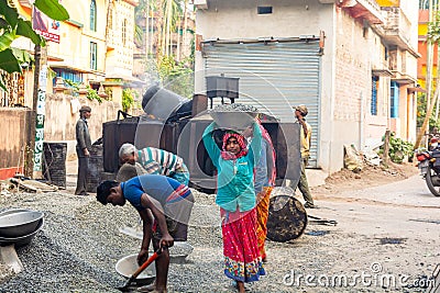 Asian construction worker carrying black stone to the asphalt mixer Editorial Stock Photo