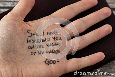 The LORD inscribed our names on the palms of His hands. Handwritten quote on hand with Holy Bible. Stock Photo