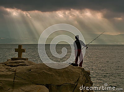 Gods rays, cross and fisherman Stock Photo