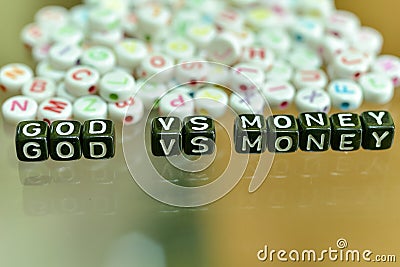 GOD VS MONEY written with Acrylic Black cube with white Alphabet Beads on the Glass Background Stock Photo