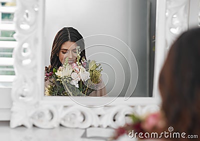 This is going to be an amazing day. a beautiful woman smelling flowers while sitting in front of the mirror. Stock Photo
