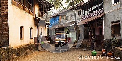 Gokarna, Karnataka, India- 29 January 2014 - yellow rickshaw and local people with jugs of water in a street. Editorial Stock Photo