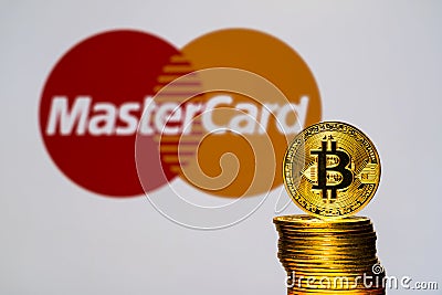 Gold Bitcoin coins with the MasterCard logo on background Editorial Stock Photo