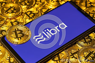 Gold Bitcoin Coins pile with the Facebook Libra Crypto Coin logo Editorial Stock Photo