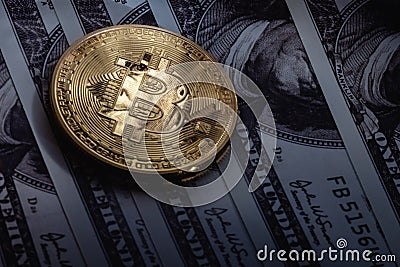 Gold bitcoin on one hundred dollar bills. The coin reflects the eyes of Benjamin Franklin Stock Photo