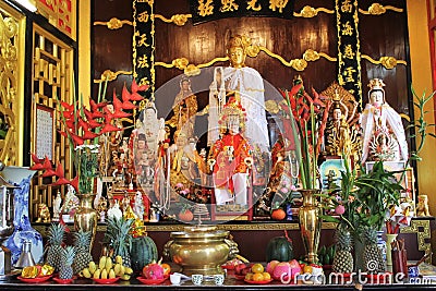 Gold Buddhist statues with red flowers and fruits Stock Photo