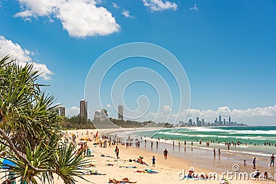 People relaxing on Burleigh beach with view of Gold Coast skyscrapers Editorial Stock Photo