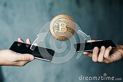 Gold coin Bitcoin payment from phone to phone, hands and TVs close-up. The concept of crypto currency. blockchain technology. Stock Photo