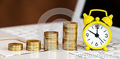 Gold coins and alarm clock on a laptop, online investment banner Stock Photo