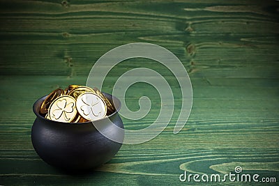 Gold coins in caldron for st. patricks day on green wooden background Stock Photo