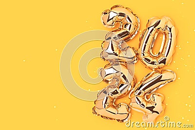 2024 gold colored inflatable balloons on a yellow background. Stock Photo