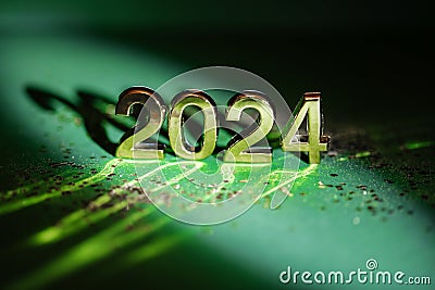 2024 gold colored numbers and glittering confetti on a vivid bright green background Stock Photo