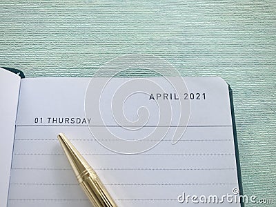 A golden pen points to the diary, 1st April 2021, Thursday, blue-green background. Stock Photo