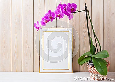 Gold decorated frame mockup with purple orchid in wicker basket Stock Photo