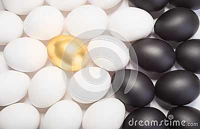 Gold Easter egg between many white and black eggs Stock Photo