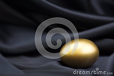Gold egg on black satin background reflects smart success Stock Photo