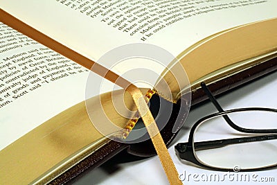 Gold Embossed Book with Reading Glasses Stock Photo