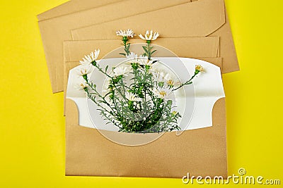 Gold envelope with a spring flower arrangement on yellow background. Flat lay, top view. Opened envelope. Stock Photo