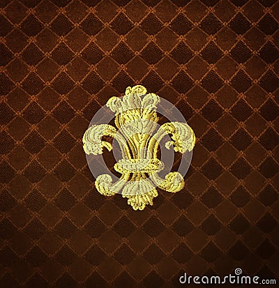 Gold Fleur-de-lis embroidered on a rust color fabric Stock Photo