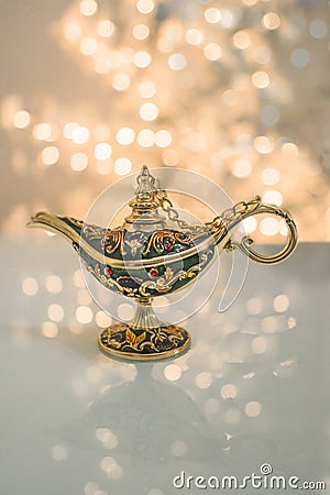 A gold genie Aladdin lamp on blurred shiny with glitter sparkle light white background Stock Photo